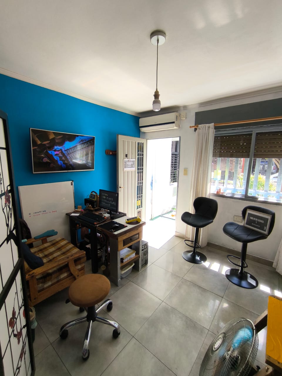 Interior del local con pared azul, escritorio de trabajo y banquetas